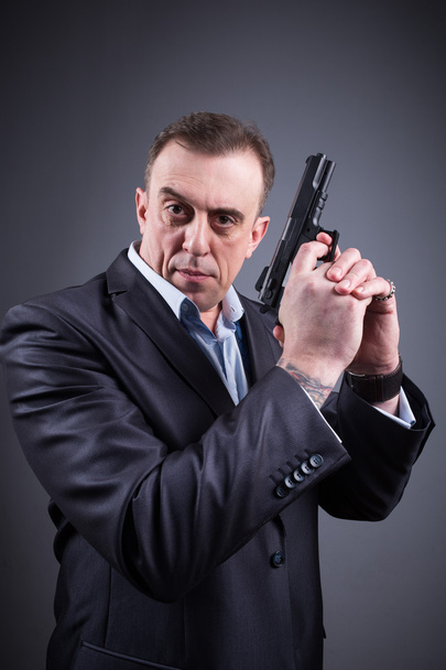 man in a business suit with a gun - Фото, изображение