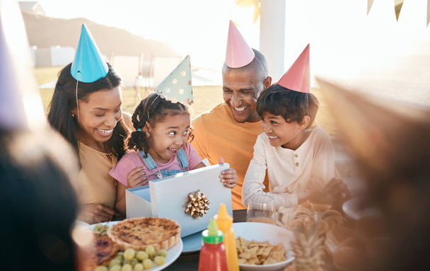 День народження, вечірка і сім'я на відкритому повітрі для святкування, зв'язку і сьогодення, щасливі і схвильовані. Батьки, діти і подарунок для дівчинки на спеціальних заходах, посмішка і святкування з їжею в ресторані
. - Фото, зображення