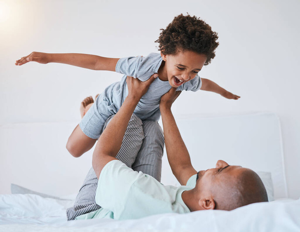 Airplane, playful and father with son in bedroom for morning, wake up and weekend. Happy, excited and funny with man and young child playing in family home for happiness, freedom and support. - 写真・画像