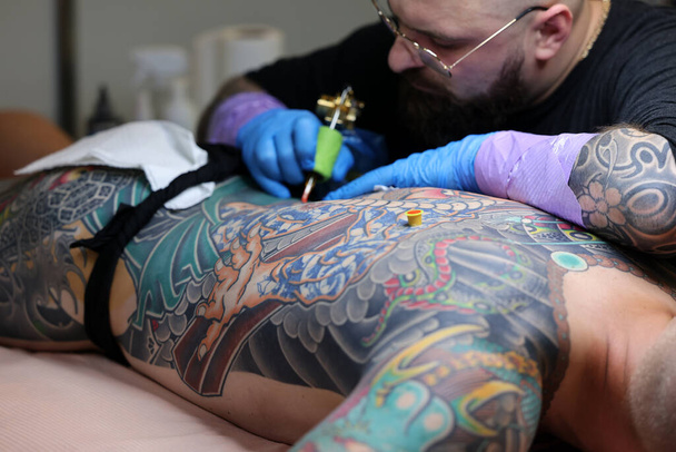 Κρακοβία, Πολωνία - 12 Ιουνίου 2022: Άγνωστος συμμετέχων στο 15ο συνέδριο Tattoofest στην Κρακοβία. Ένα από τα πιο διάσημα φεστιβάλ τατουάζ. Καλλιτέχνης τατουάζ στη δουλειά.  - Φωτογραφία, εικόνα