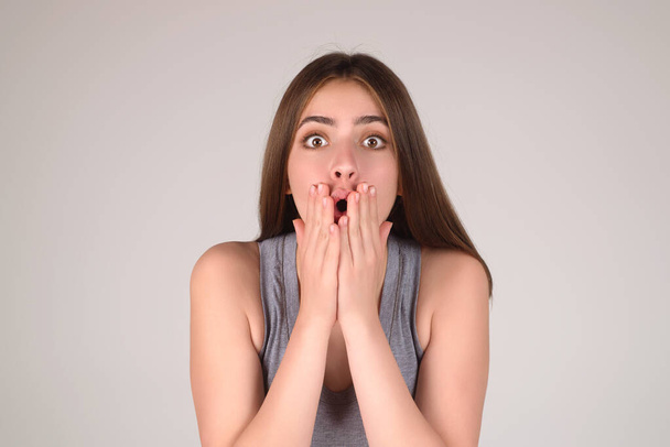 Shocked face of woman shouting WOW, isolated on studio background with copy space. Shock content. Girl looks with terrified expression, shocking news. Woman shocked face with open mouth and big eyes - Foto, Imagen