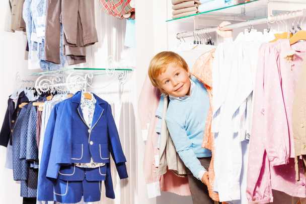 Boy plays hide-and-seek in clothes store - Fotó, kép