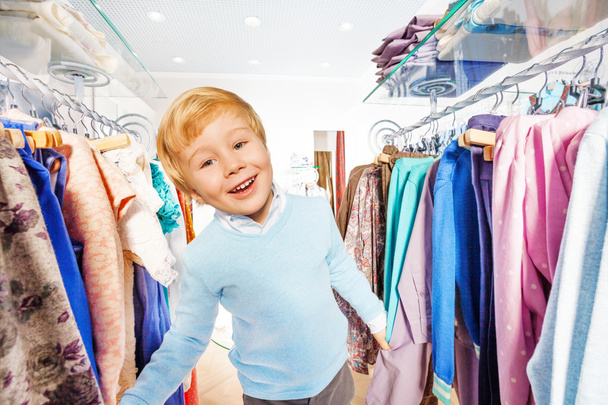 Blond small kid stands between hangers - Photo, Image