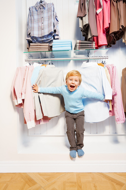 Boy standing among clothes in  shop - Foto, Imagem