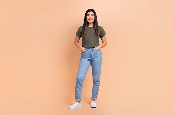 Full size photo of gorgeous satisfied glad malaysian girl put hands pockets posing isolated on beige color background. - Фото, изображение