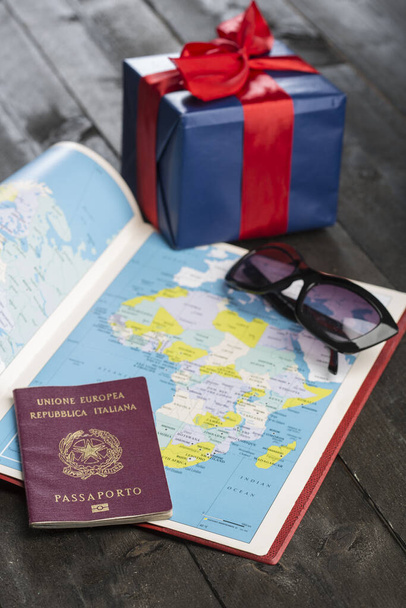 Olasz útlevél más tárgyak melletti asztalra helyezve, egy földrajzi térképpel együtt - Fotó, kép