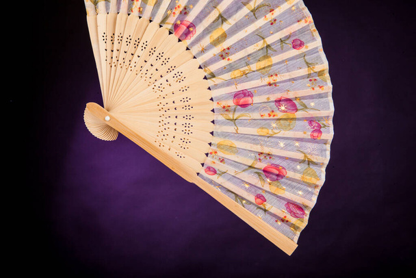 Fan with floral designs on a dark purple background - Photo, Image