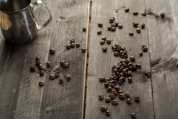 кавові зерна і металева чашка на дерев'яному столі
 - Фото, зображення