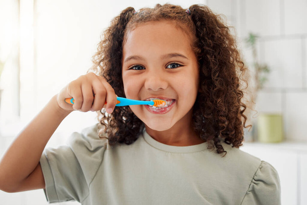 Toothbrush, brushing teeth and portrait of a child in a home bathroom for dental health and wellness with smile. Face of Latino girl kid learning to clean her mouth for morning routine and oral care. - Фото, изображение