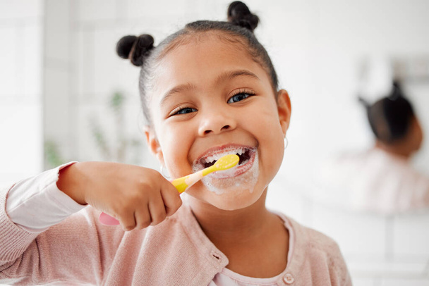 Toothbrush, brushing teeth and face of a child in a home bathroom for dental health and wellness. Smile portrait of african girl kid cleaning mouth with a brush for morning routine and oral self care. - Φωτογραφία, εικόνα