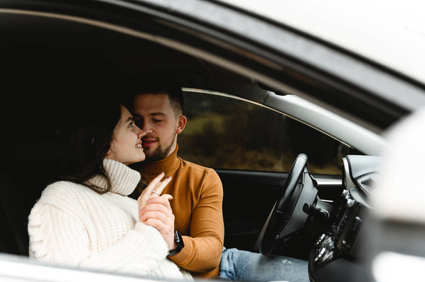 Χαριτωμένο ζευγάρι αγκαλιάζει ενώ στο αυτοκίνητο. οδικό ταξίδι των εραστών. Φθινοπωρινή περίοδος - Φωτογραφία, εικόνα