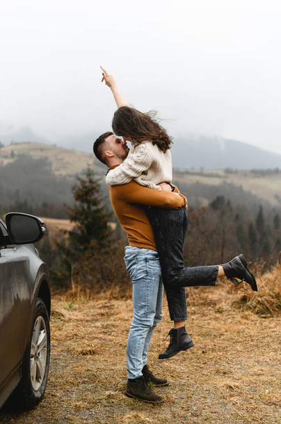 a couple in the autumn time having fun traveling. a man holds a girlfriend in his arms. happy couple on high ground. couples autumn vacation - Foto, Imagen