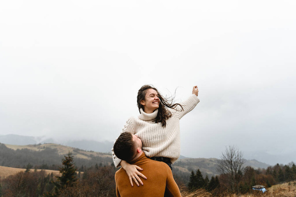 lovers in warm sweaters in autumn gently hug while traveling. adventure of a man and a young woman. - Foto, imagen