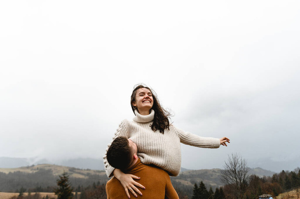 a couple in the autumn time having fun traveling. a man holds a girlfriend in his arms. happy couple on high ground. couples autumn vacation - Photo, image