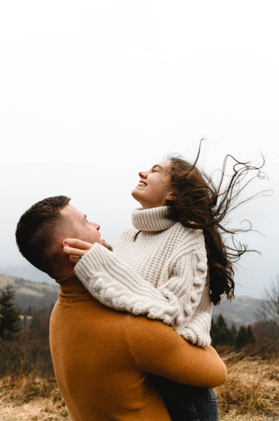 lovers in warm sweaters in autumn gently hug while traveling. adventure of a man and a young woman. - Foto, immagini