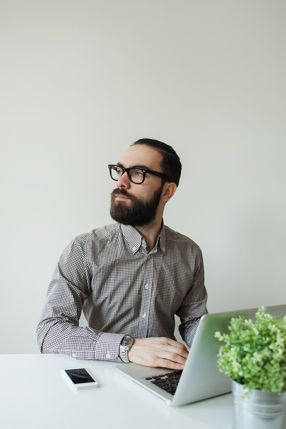 Busy man with beard in glasses thinking over laptop and smartpho - 写真・画像