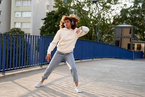 Wide shot of black woman wearing headphones and dancing on the bridge - Фото, зображення