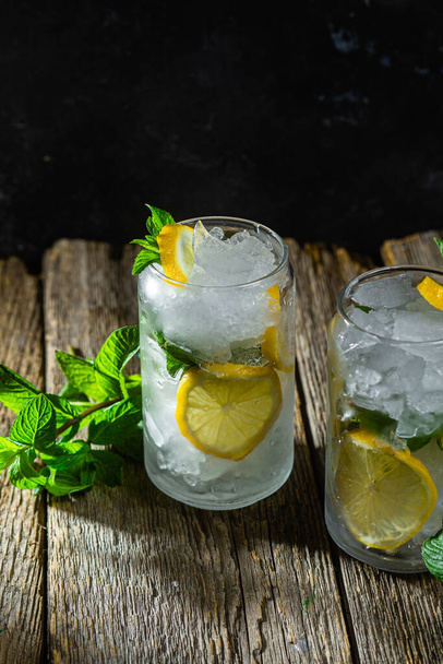 Koude limonade met munt en citroen en ijs op een donkere achtergrond - Foto, afbeelding