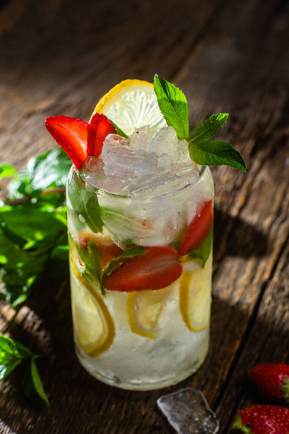 Cold lemonade with mint and lemon and ice on a dark background - 写真・画像