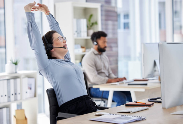 Customer service, woman with headset and stretching her arms at her desk with a computer of modern workplace. Online communication, telemarketing and female call center agent stretch for fatigue. - Foto, immagini