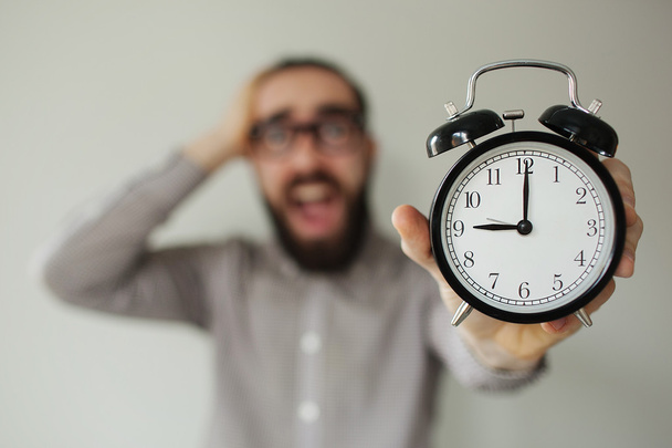 Man in panic holds alarm clock and head in fear of deadline - Foto, Imagen
