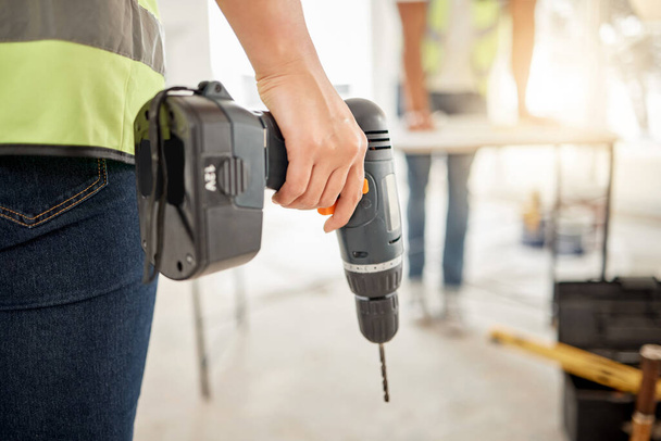 Drill, construction and hand of handyman for home renovation, maintenance or carpenter work. Back of engineer, constructor or contractor person with electric power tools in room or building site. - Photo, Image