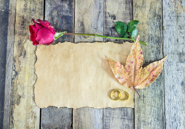 Zblízka zlatý prsten, červené růže, suché listí a starý papír na dřevěné - Fotografie, Obrázek