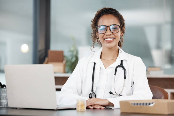 Doctor, woman in portrait and happy, healthcare and medical professional in office with stethoscope and laptop. Female person in medicine, desk and health insurance with cardiologist at hospital. - Foto, Imagen