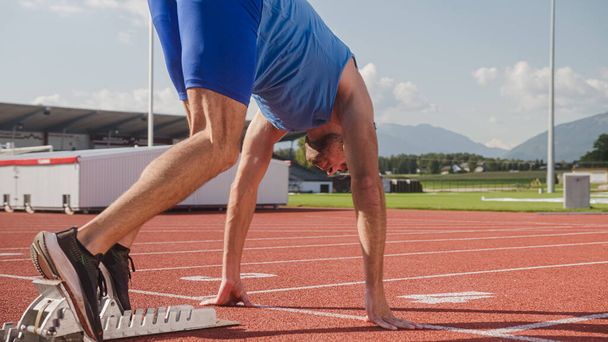 Sideways view male professional athlete preparing beyond start line in a starting block and running - Φωτογραφία, εικόνα
