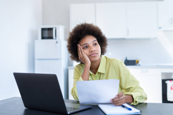 Stressaantunut nuori musta nainen hukassa raskaisiin ajatuksiin pidä paperi asiakirja käsitellä velan konkurssiin ajatella ratkaista rahaongelma. Huolestunut sekarotuinen nainen huolissaan huonoista uutisista, jotka on saatu kirjeitse - Valokuva, kuva