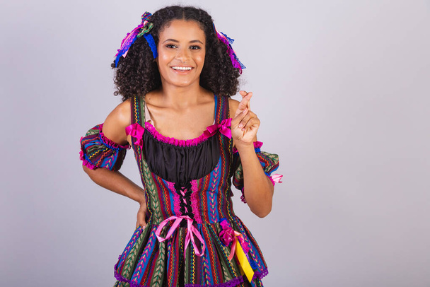 Mujer brasileña negra con ropa de fiesta junina. Comunidad de San Juan. Arraial, dedos cruzados, animando, deseando. - Foto, Imagen