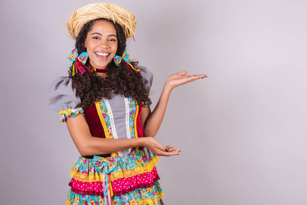 Black, Brazilian woman, wearing June party clothes, fraternization in the name of So Joo, Arraial. presenting product or advertisement on the side - Valokuva, kuva