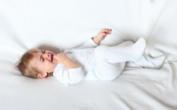 Worried crying child lying on a bed. - Valokuva, kuva