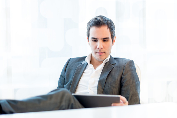 Serious young businessman reading his tablet-pc - Photo, Image