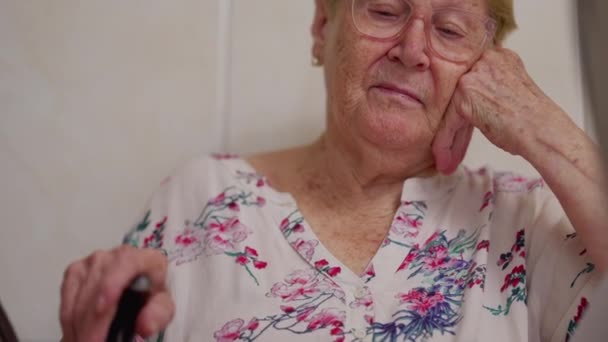 Töprengő nyugdíjas idős hölgy otthon mély elmélkedéssel. Idős nő emlékszik a múlt emlékeire, miközben kéz az arcon gondolkodik. - Felvétel, videó