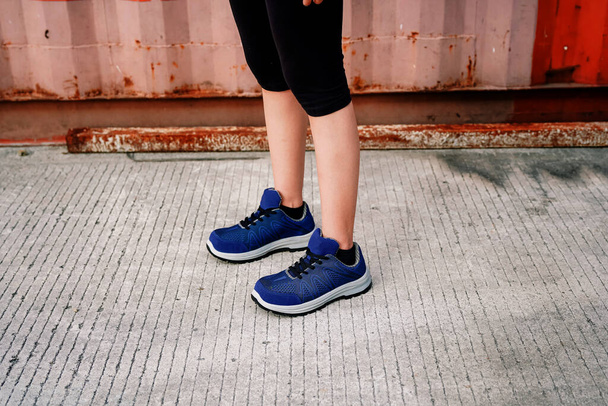 Photo of a woman standing and wearing sports shoes, these shoes are often called sneakers - Foto, immagini