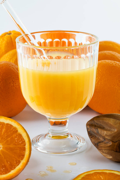 szklankę świeżo wyciskanego soku pomarańczowego ze słomką szklaną, oprawioną w świeże pomarańcze - Zdjęcie, obraz