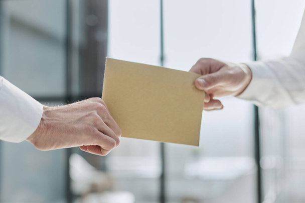 Cropped photo of a stylish man handing over a sealed paper envelope - Foto, Imagen