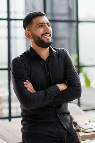 young businessman smiling in the office with his arms crossed - Фото, изображение
