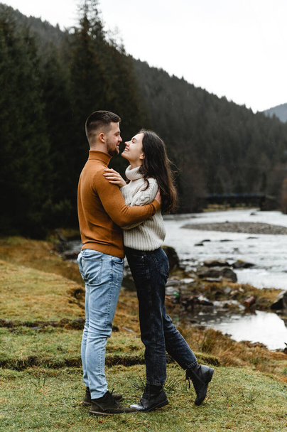couple outdoors in the autumn season. lovers walk in a mountainous area near the river and forest. pastime of lovers during travel - Foto, immagini