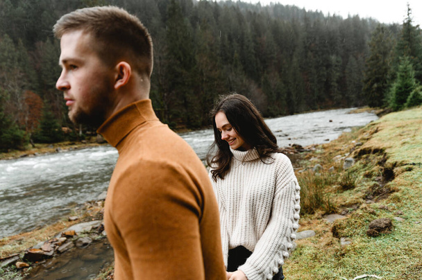 couple outdoors in the autumn season. lovers walk in a mountainous area near the river and forest. pastime of lovers during travel - Photo, image
