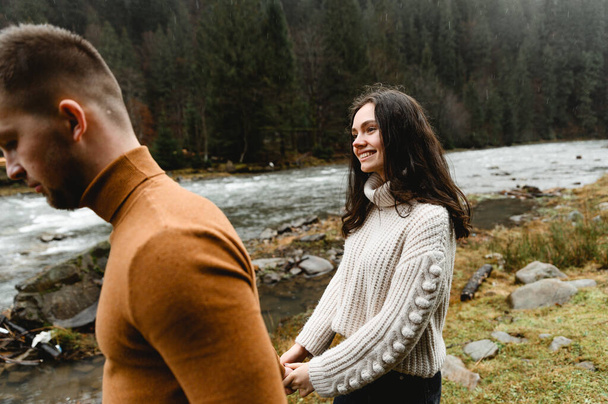 couple outdoors in the autumn season. lovers walk in a mountainous area near the river and forest. pastime of lovers during travel - Foto, Imagen