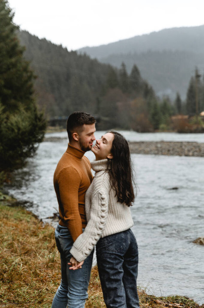 couple outdoors in the autumn season. lovers walk in a mountainous area near the river and forest. pastime of lovers during travel - Foto, Bild