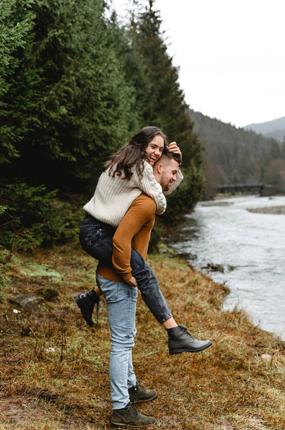 couple outdoors in the autumn season. lovers walk in a mountainous area near the river and forest. pastime of lovers during travel - Foto, Imagen