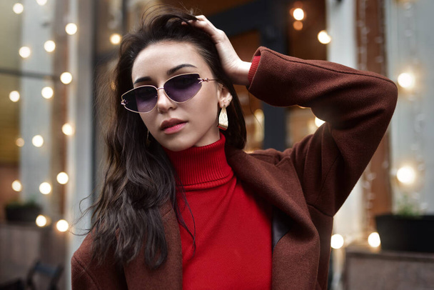 Portrait of a Woman in sunglasses fixing her hair on the street. - 写真・画像