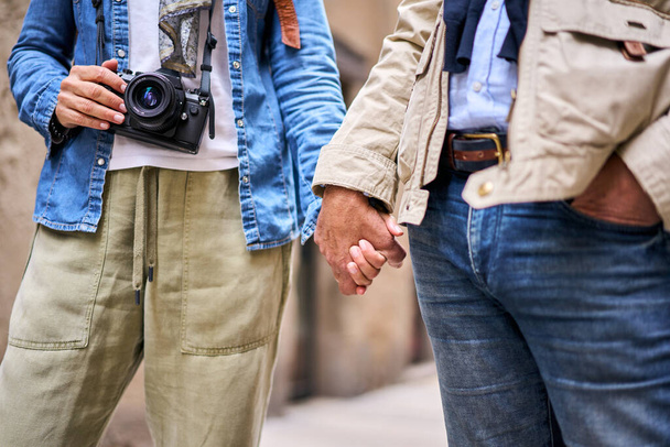 Nahaufnahme Porträt eines nicht wiederzuerkennenden reifen Paares, das im Freien Händchen hält. Anonyme erwachsene Touristen genießen ihren Urlaub. Beziehung und Reisekonzept.  - Foto, Bild