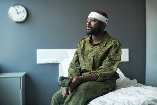 Nuori afroamerikkalainen stressaantunut sotilas, jolla oli side päässä, istui vuoteella sairaalaosastolla, katsoi ikkunasta ja ajatteli: - Valokuva, kuva