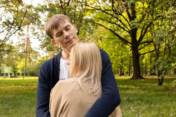 Beautiful Couple Stands Hugging With Closed Eyes In Green Park. Relationship, Togetherness. Enjoying Time Together, Harmony. Pure Feelings. Horizontal Plane Summer Time. High quality photo - Photo, Image