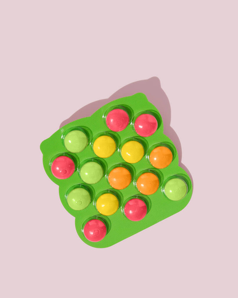 Kerek színes tabletták buborékcsomagolásban rózsaszín alapon  - Fotó, kép