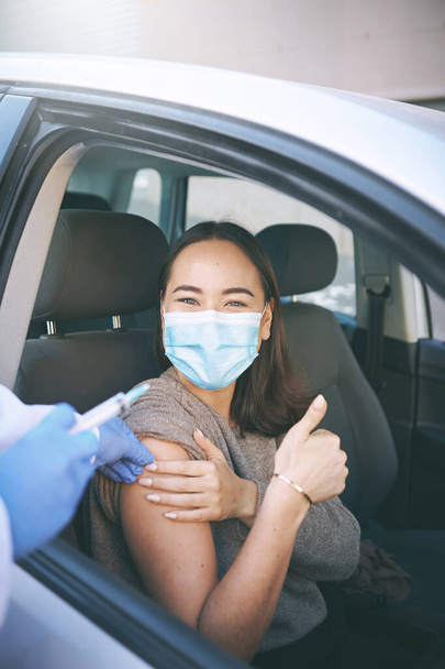 Say no to the virus and yes to the vaccine. a masked young woman receiving an injection at a Covid-19 drive through testing centre - Foto, Imagen